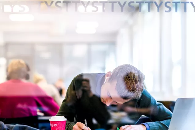 Student som pluggar, böjd över sin bänk. Foto.